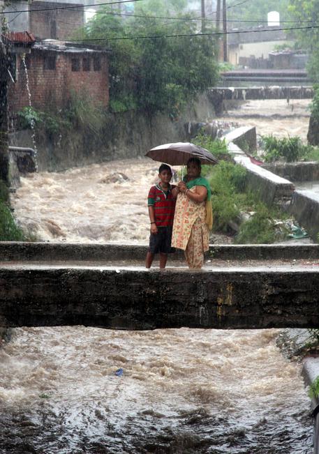 epa05461075 Indian people hold an umbrella to protect themselves from rain during flash floods on the outskirts of Jammu, the winter capital of Kashmir, India, 07 August 2016. According to the news reports, a flood alert was sounded in Jammu as River Tawi was flowing at danger mark of 18 ft, while river Chenab was few centimeters from danger mark of 30.5 feet after incessant rains in the region. EPA/JAIPAL SINGH